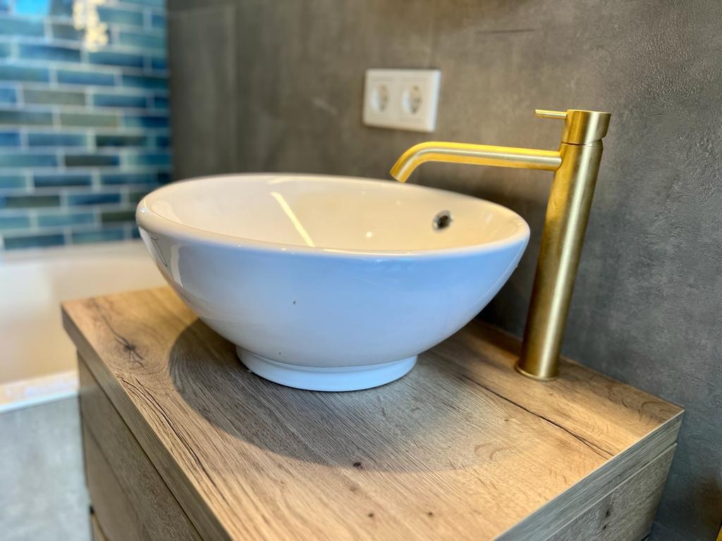 Stijlvolle waskom met moderne kraan, geplaatst op een strak badkamermeubel.