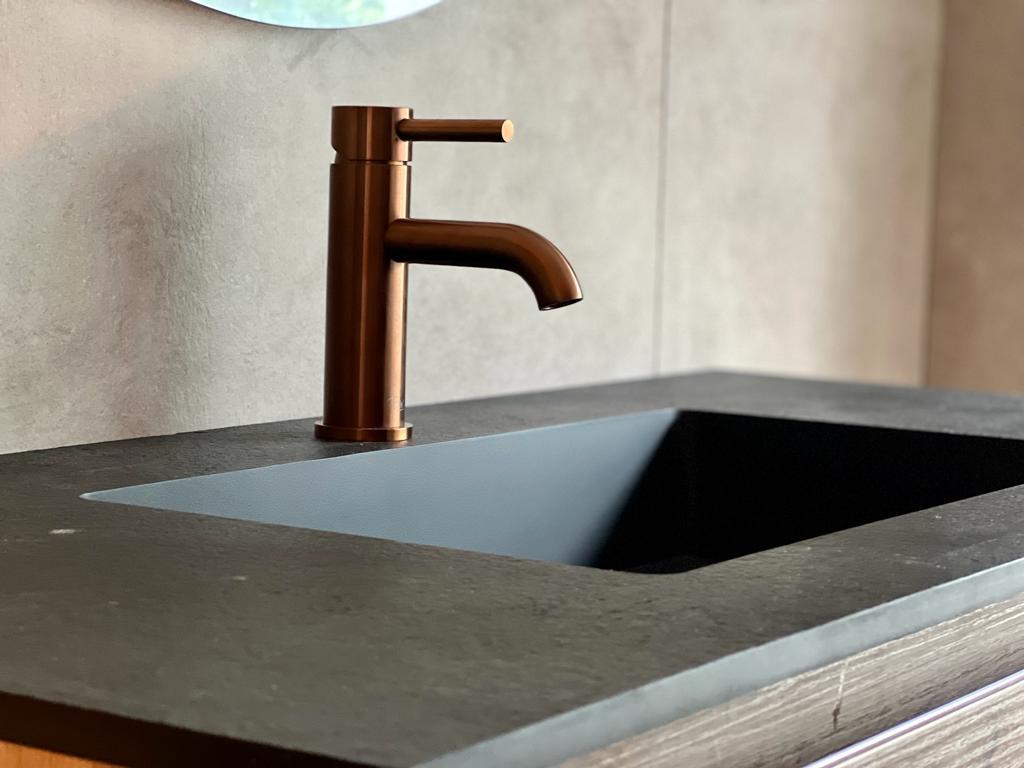 Rosékleurige kraan boven een strakke wasbak. 