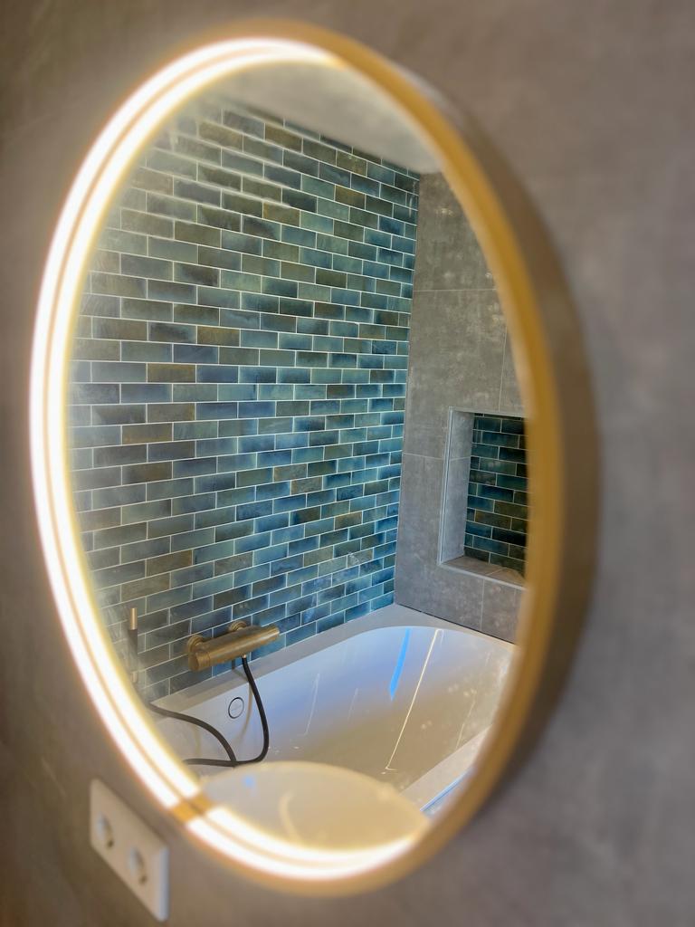 Prachtige spiegel in een modern gerenoveerde badkamer met strakke lijnen en sfeervolle verlichting.
