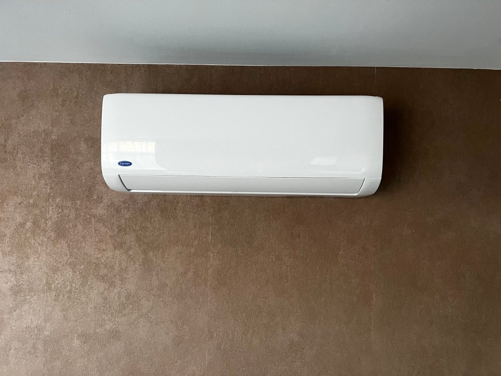 Witte binnenunit, wandunit, van een Carrier airconditioningsysteem, gemonteerd aan de muur in een kamer.