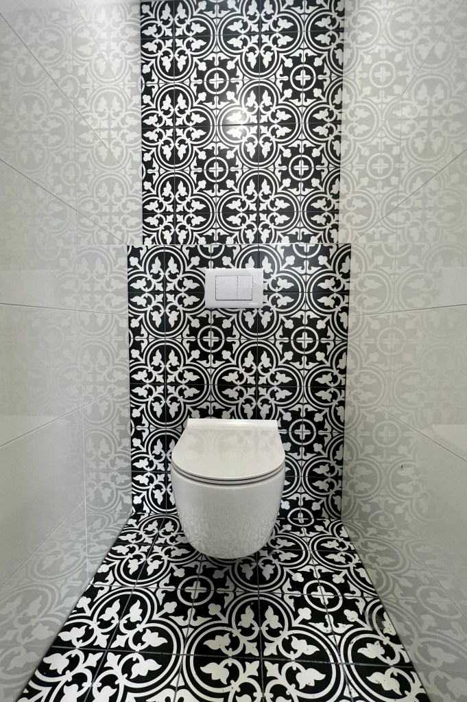 Toiletrenovatie met een stijlvol hangtoilet, gecombineerd met zwart-witte designtegels voor een moderne en frisse uitstraling.
