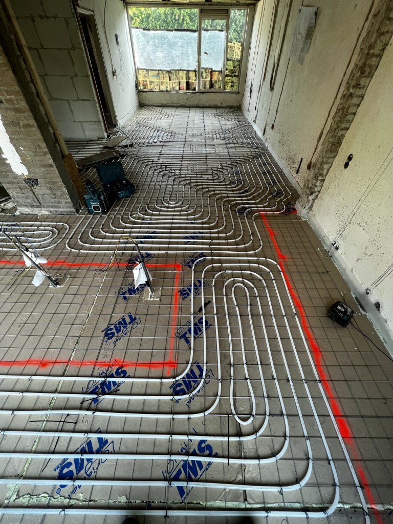 Traditionele vloerverwarming op netten in slakkenhuis patroon, geïnstalleerd als primaire verwarming voor gelijkmatige warmteverdeling.