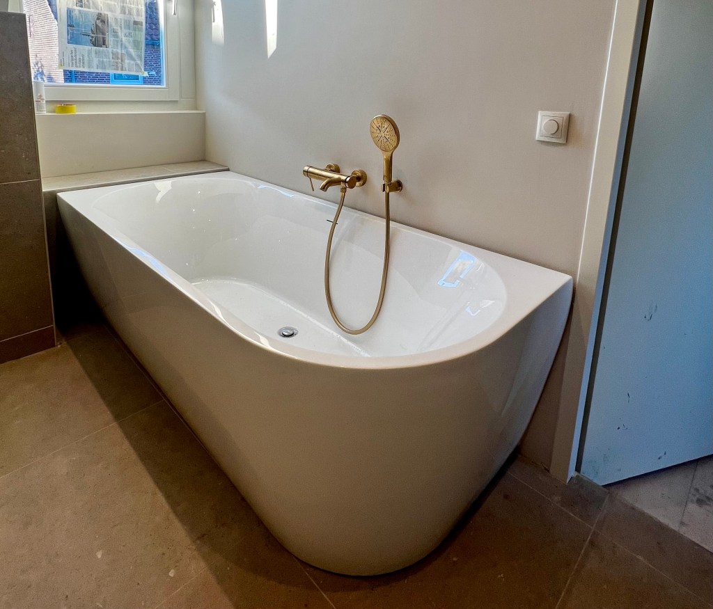 Bad met gouden kraan en douchekop.