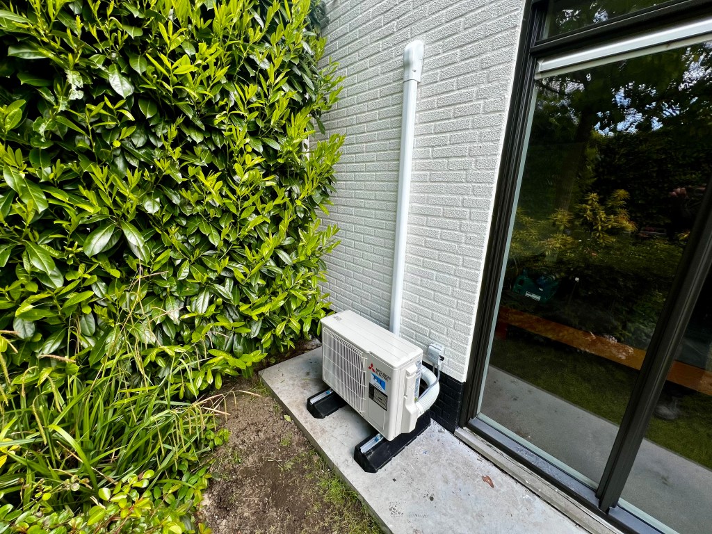 Buitenunit van een Mitsubishi Electric airconditioningsysteem. De unit heeft een robuust en modern ontwerp, met het Mitsubishi Electric-logo zichtbaar aan de voorkant, ontworpen voor efficiënte koeling en verwarming.