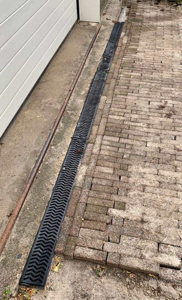 Afbeelding van een draingoot in straatwerk, bedoeld voor afwatering en het afvoeren van regenwater via het rioleringssysteem. De draingoot is zichtbaar langs de straat en leidt het water efficiënt af om te zorgen voor een goede afvoer en bescherming tegen wateroverlast.