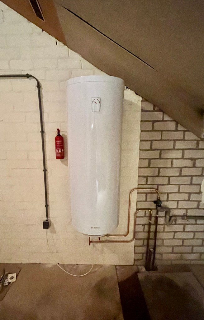Warmwaterboiler met elektra, waterleiding, afvoer en riolering geïnstalleerd in een ruimte.